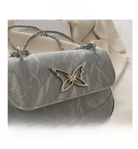 Detail of grey marble pattern leather bag featuring a metal butterfly buckle and silver chain