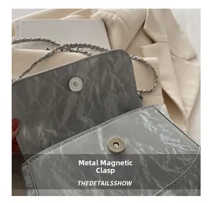 Detailed macro view of the silver magnetic snap closure on a grey pleated chain bag