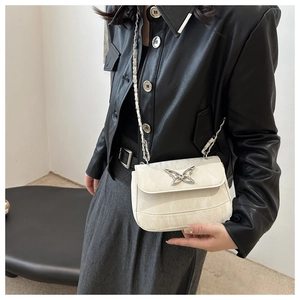 Detail of white textured crossbody bag with silver butterfly buckle on black jacket