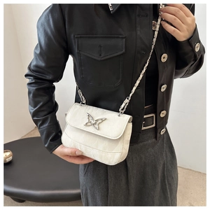Detail of minimalist white crossbody bag with marble texture and silver butterfly buckle