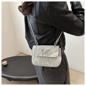 Detail of silver metallic wrinkled leather crossbody bag with oversized butterfly clasp