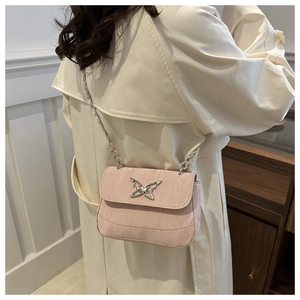 Pink crossbody bag with silver butterfly buckle shown on model wearing cream trench coat