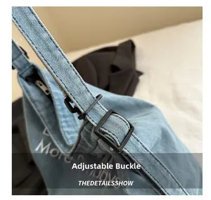 Detail showing the adjustable black buckle on the light blue denim tote shoulder bag