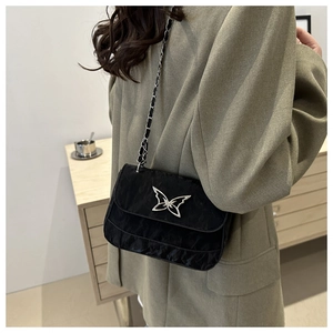 Detail of black pleated crossbody bag featuring a silver butterfly buckle on a model