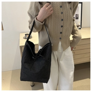 Détail d'un sac seau en denim noir minimaliste avec cordon décoratif et fine bandoulière