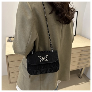 Detail of black pleated crossbody bag with silver butterfly buckle and chain strap