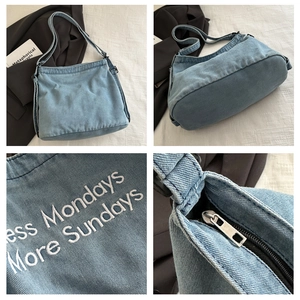Detail of light blue denim tote with Less Mondays More Sundays embroidery and silver zipper