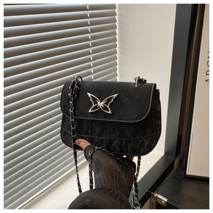 Close-up of black pleated crossbody bag with silver butterfly and chain strap detail