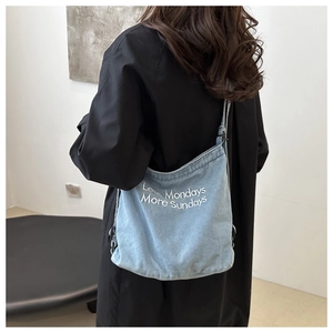 Detail of light blue denim tote with Less Mondays More Sundays white embroidery