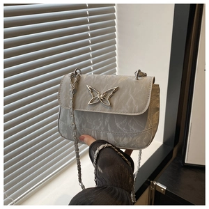 Detail of grey crossbody bag with crinkled texture and silver butterfly buckle clasp