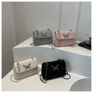 Close-up of textured crossbody bags with silver butterfly buckles and metal chains