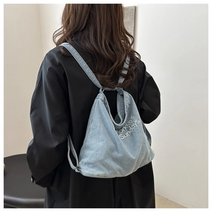 Detail of light blue washed denim tote bag with Mondays Sundays embroidery on shoulder strap
