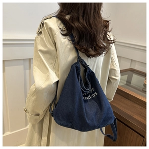 Close-up of deep blue denim shoulder bag with white Friday Sundays embroidery details