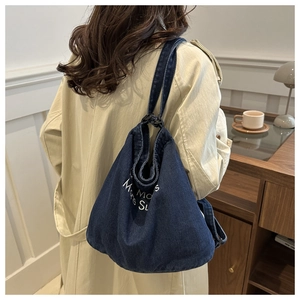 Close-up of blue denim tote bag with white text print on soft casual shoulder strap