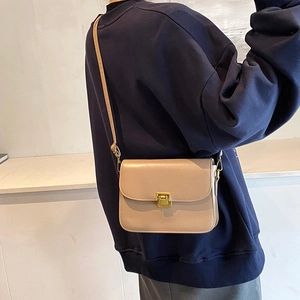 French vintage beige crossbody square bag with gold buckle on a model wearing a navy hoodie