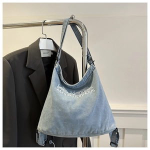 Detail of light blue denim tote bag featuring Less Mondays More Sundays embroidery