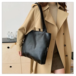 Close-up of black retro tote bag with vintage wrinkled texture and gold zipper details