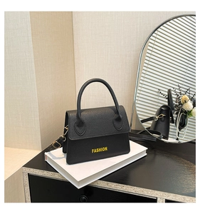 Detail of black lychee grain leather mini bag with yellow FASHION text and gold buckle