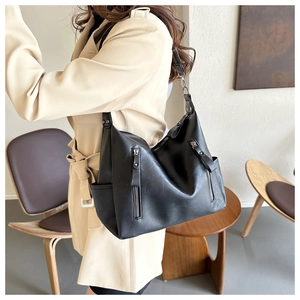 Detail of black large faux leather hobo bag featuring vertical zippers and side pockets