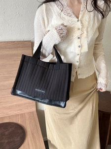 Chic black quilted tote bag with stitched stripes and fashion label for daily commute