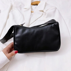 Detail of minimalist black baguette bag with gold zipper and smooth faux leather texture