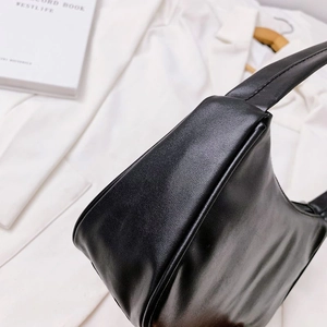 Detail of the black leather shoulder bag showing side profile and fine stitching texture