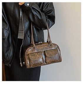 Close-up of brown vintage leather shoulder bag with two front pockets on a model