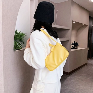 Model wearing a stylish bright yellow underarm bag with minimalist shoulder strap design