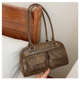 Detail of vintage brown leather handbag with two front pockets and silver ring hardware
