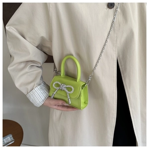 Mini lime green crossbody bag with a sparkling rhinestone bow and silver chain strap