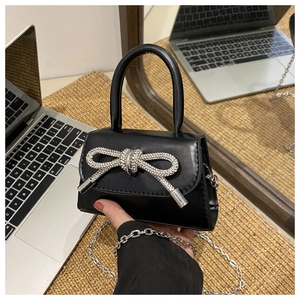 Close-up of a mini black leather bag with a sparkling silver rhinestone bow detail