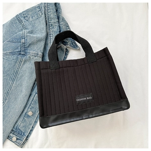 Detail of black quilted tote bag featuring leather bottom and Fashion Bag label