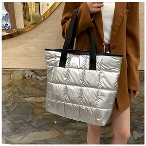 Sac cabas argenté matelassé avec grands carreaux et bandoulière noire sur modèle
