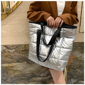 Sac fourre-tout matelassé argenté avec poignées en nylon noir porté dans un décor chic
