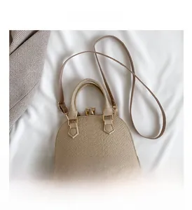 Detailed macro of beige faux leather shell bag with refined crocodile pattern and gold zipper