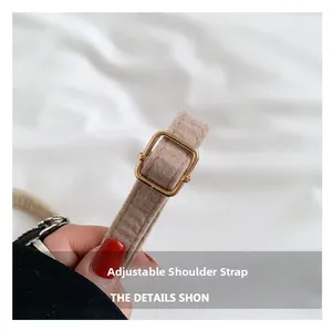 Detail of adjustable beige felt shoulder strap with gold buckle on shell bag