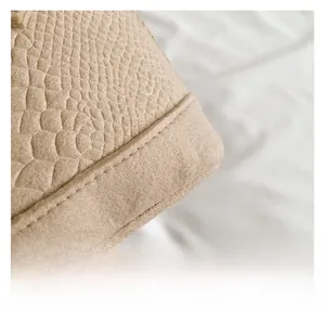 Macro shot of beige crocodile embossed leather with neat stitching on a shell bag