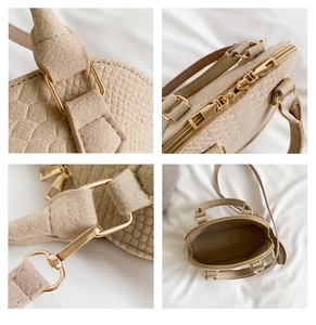 Detail view of gold metal zippers and crocodile texture on beige crossbody shell bag