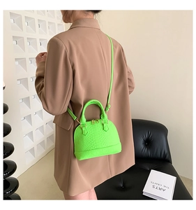 Detailed view of neon green shell bag with snakeskin texture and gold hardware details
