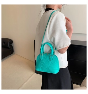 Detail showing mint green shell bag with snakeskin texture and golden hardware accents