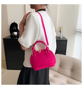 Detail of rose red shell bag with animal embossed texture and golden metal hardware