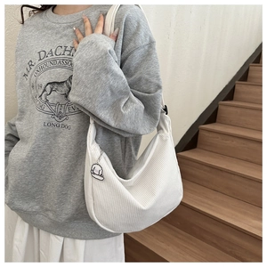 Close-up of white corduroy crescent bag with cute charm on a wooden staircase