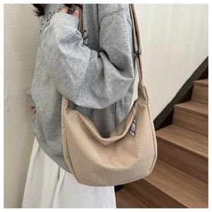 Detail of beige corduroy hobo shoulder bag with zipper closure and cute lamb charm