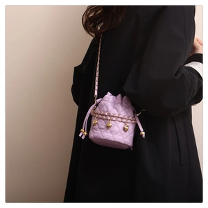 Detail view of lavender quilted bucket bag with gold chain and heart charms on model
