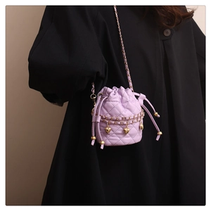 Détail du sac seau matelassé violet avec breloques cœur dorées et bandoulière chaîne