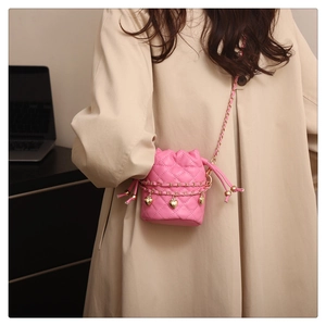 Close-up of pink quilted bucket bag with gold heart pendant and chain strap detail