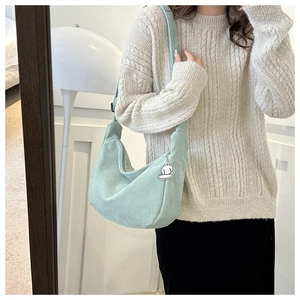 Detail of light green corduroy crescent bag with a cute white plush puppy charm