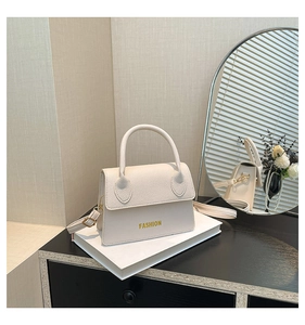 Close-up of beige lychee texture handbag with gold fashion logo and top handle