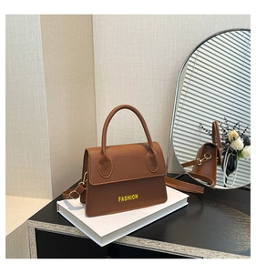 Detail of classic brown faux leather handbag with lychee texture and round top handle