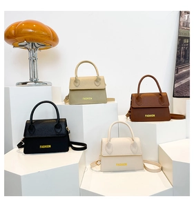 Detail view of leather crossbody bags in black, khaki, brown, and cream with gold accents